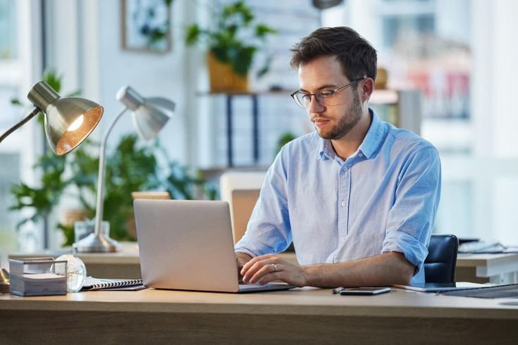 Seseorang sedang bekerja menggunakan laptop dan smartphone untuk strategi digital marketing