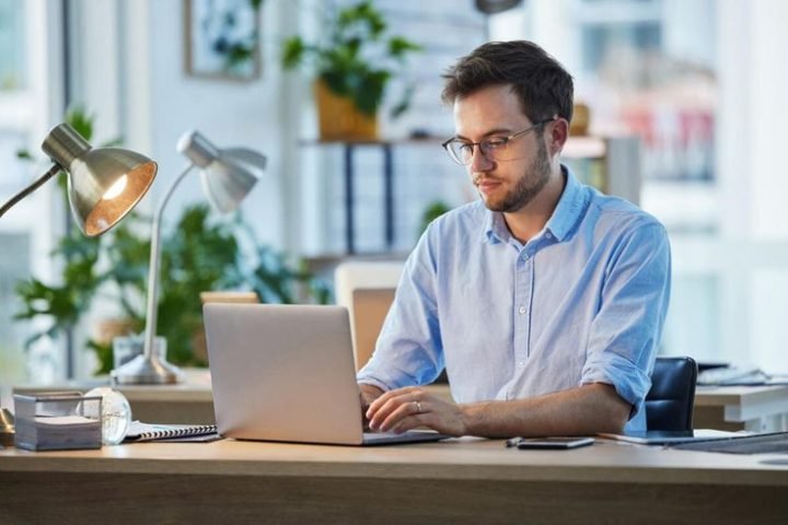 Seseorang sedang bekerja menggunakan laptop dan smartphone untuk strategi digital marketing